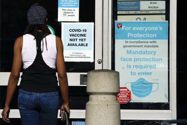 Customer walks past a sign indicating that a COVID-19 vaccine is not yet available at Walgreens, in Long Beach, California.